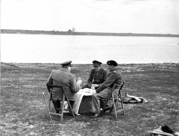British prime minister Winston Churchill (l) talks to Field Marshal Bernard Law Montgomery (r) and Field Marshall Sir Alan Brooke (m) in March 1945, shortly before the end of the war, during an improvised picnic on the shores of the Rhine in the Netherlands.